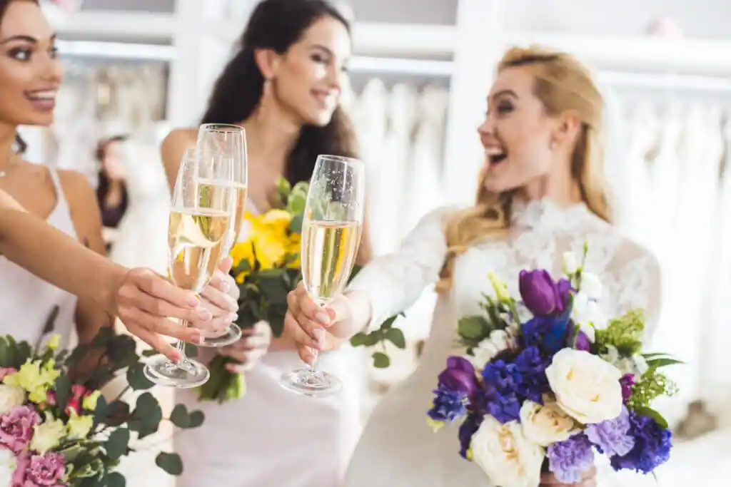 happy women in wedding dresses toasting with champagne
